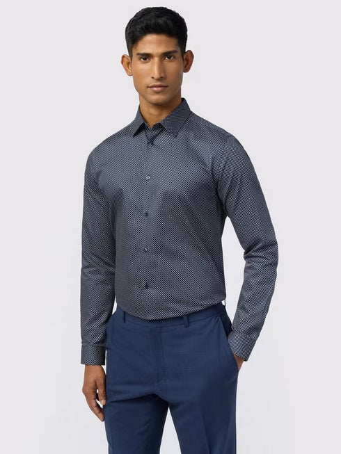 Man wearing a dark blue patterned shirt and pants on a light gray background