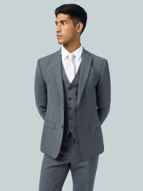 Man wearing a gray suit with a white shirt and pink tie on a light gray background