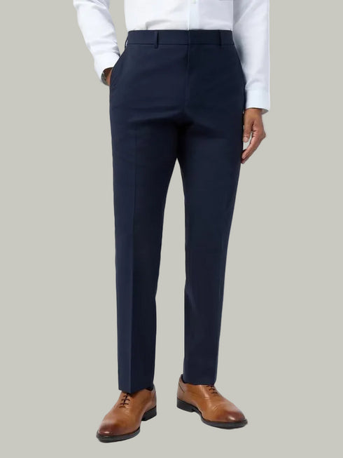 Navy suit pants worn with a white shirt and brown shoes on a white background