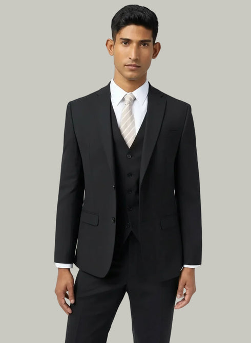 Man wearing a black suit with a white shirt and tie on a light gray background