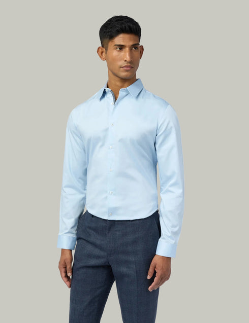 Man wearing a light blue shirt and dark pants on a white background