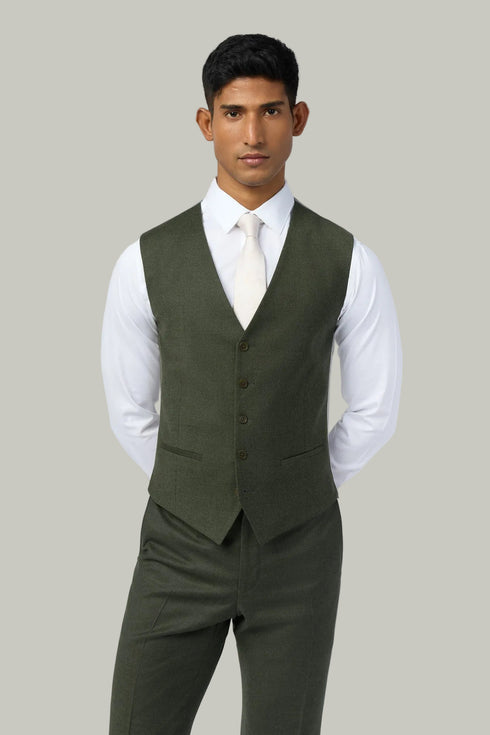 Man wearing a green vest over a white shirt on a light gray background