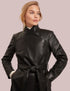 Woman wearing a black leather coat against a plain background